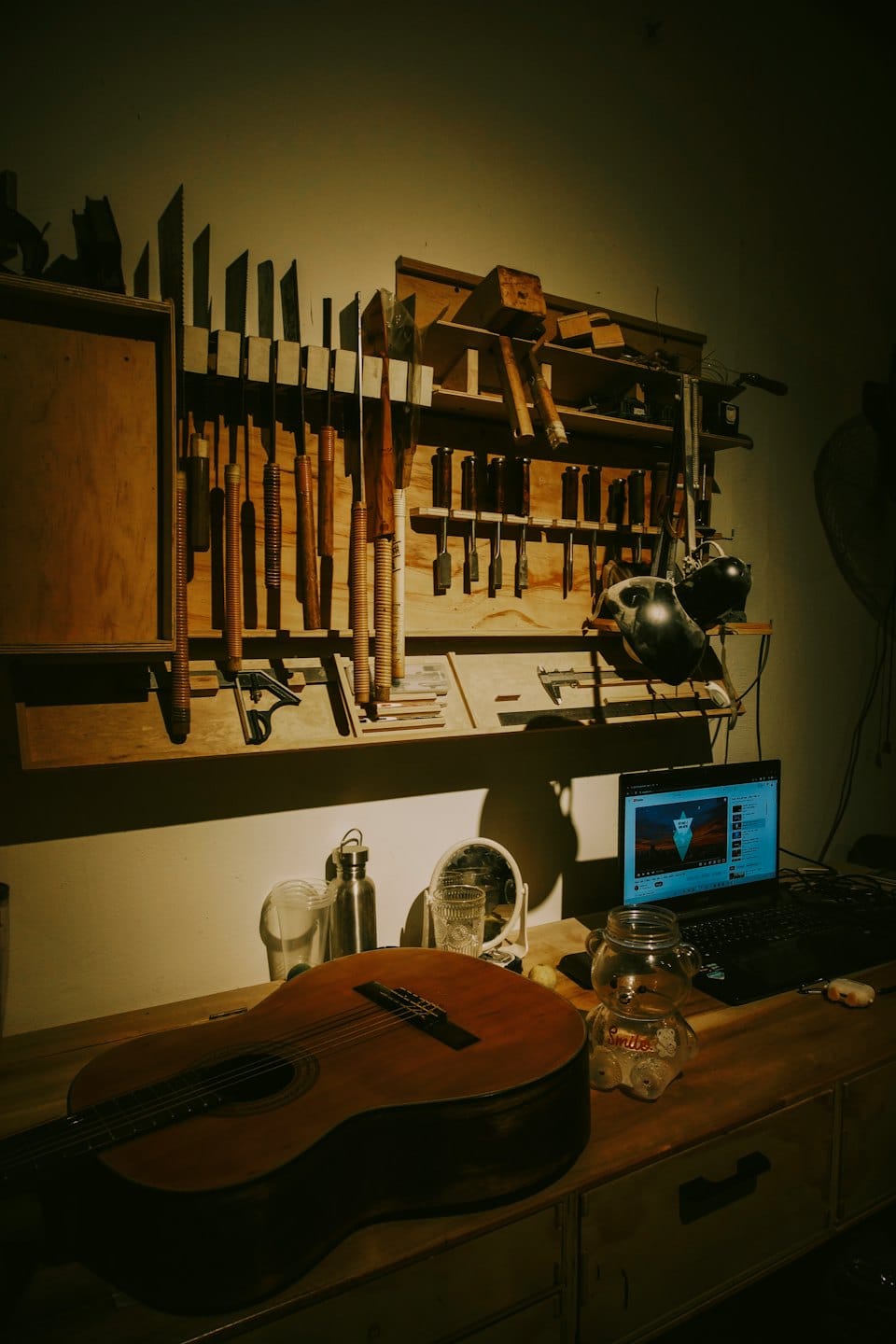 Eine hölzerne Werkbank mit einer klassischen Gitarre und verschiedenen Holzbearbeitungswerkzeugen.