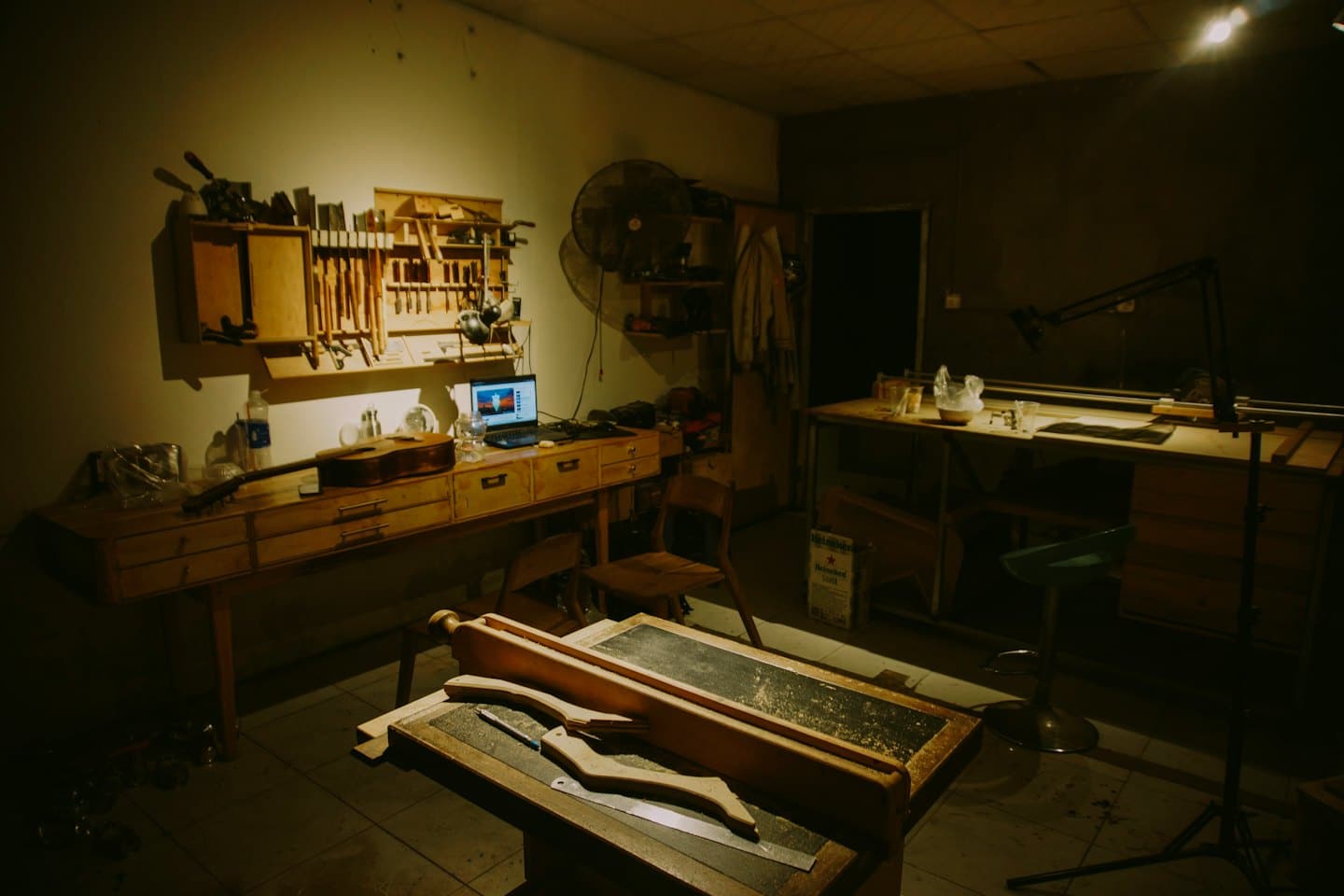 Eine Akustikgitarre und ein Laptop stehen auf der Holzwerkbank eines Gitarrenbauers.